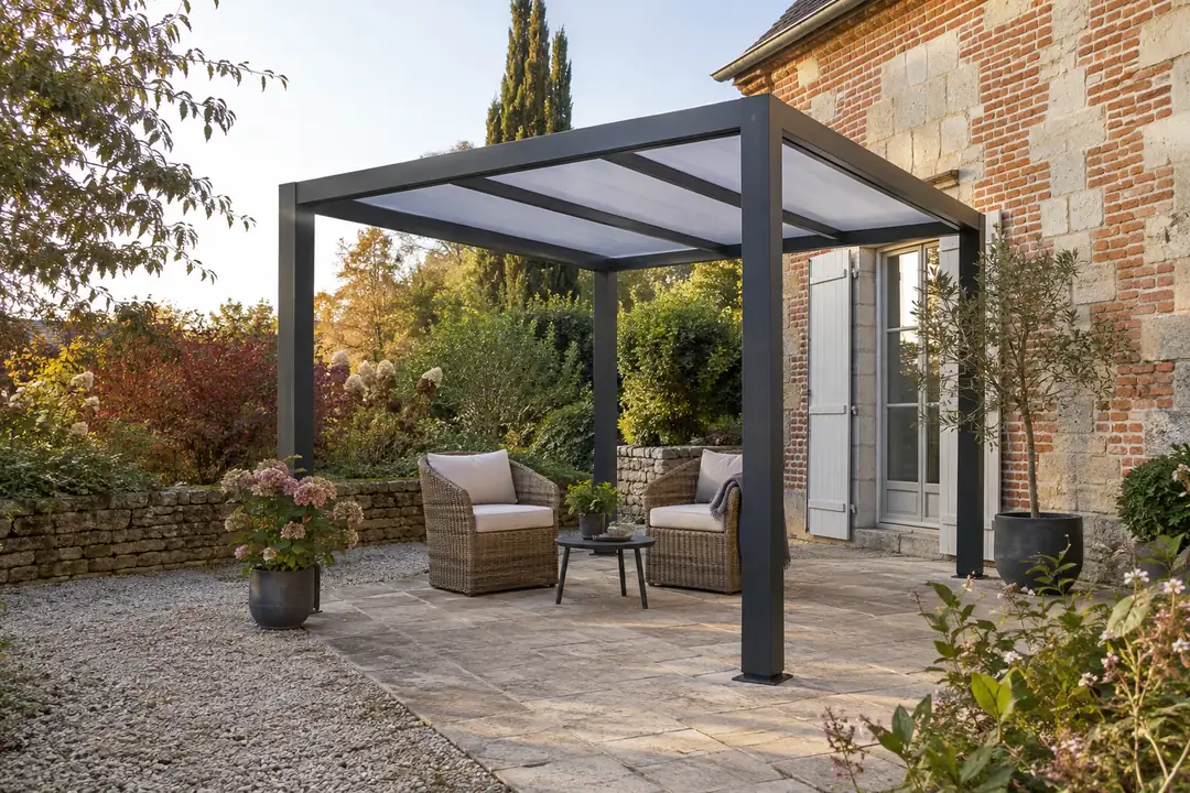 Pergola aluminium à toit translucide dans un jardin, contre un mur de pierre et de brique